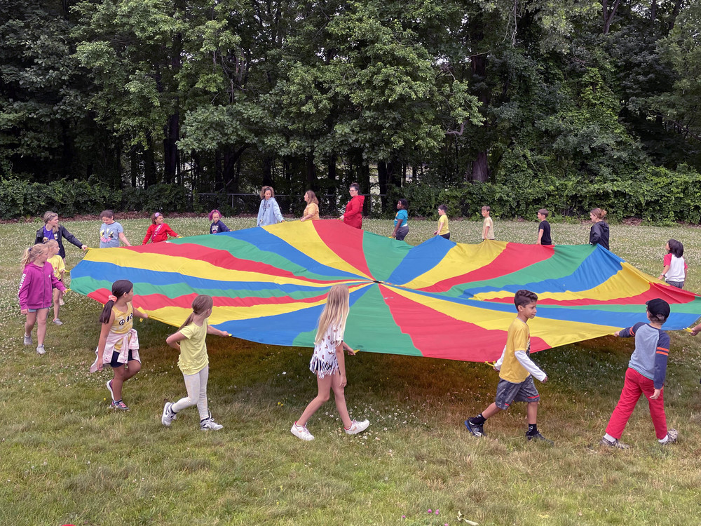 students holding giant colorful parachute