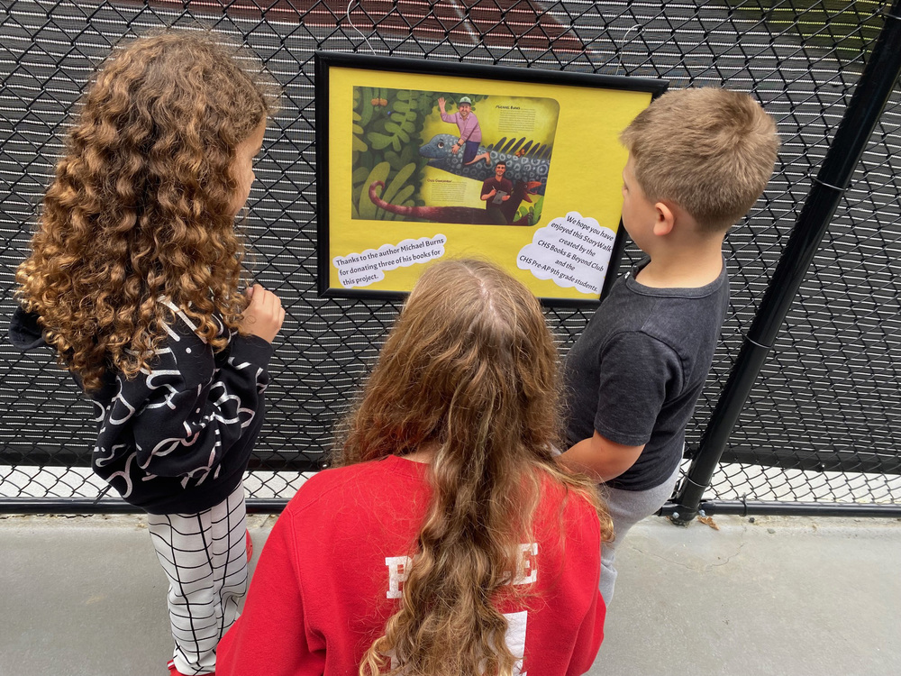 students looking at story page hanging on fence