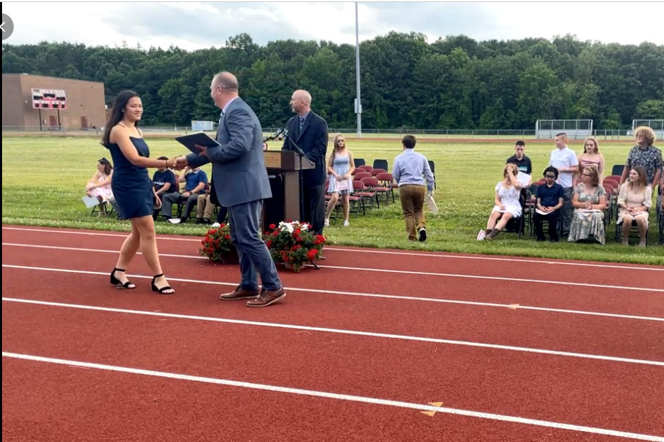 girl shaking hands with man during 8th Grade Moving Up Ceremony