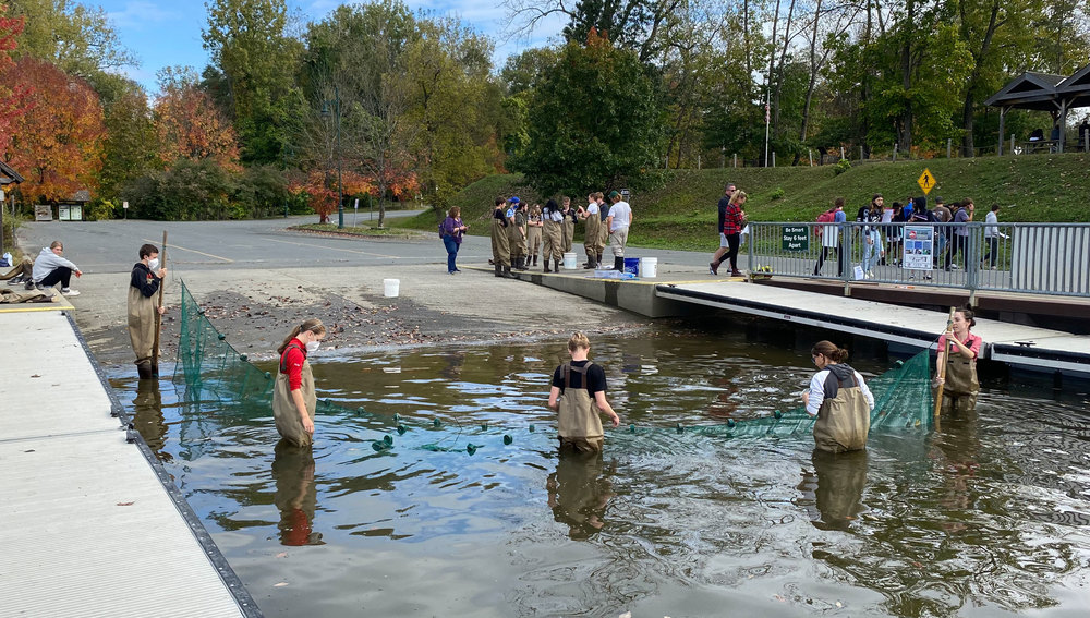 students wading in river with net