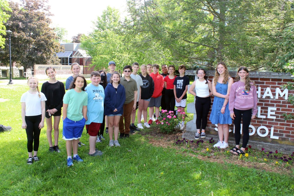 Students pose with rose bush nest to school sign