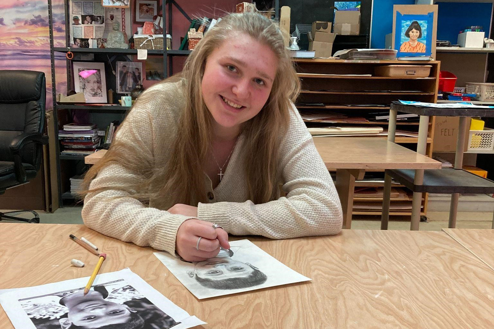 teenage girl drawing portrait of Indian child