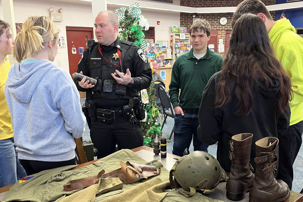 Police officer and students looking at militaria on table
