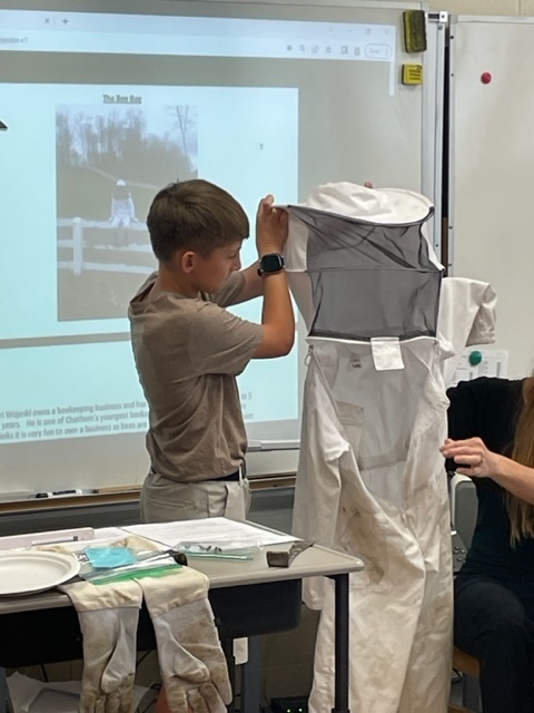 boy holding up bee suit