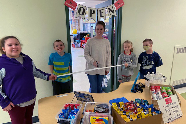 students and teacher cut the ribbon on school store