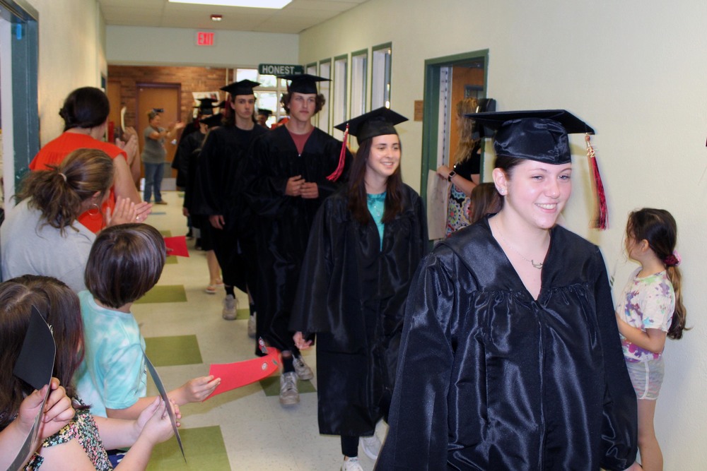 seniors walking through hallway in caps and gowns
