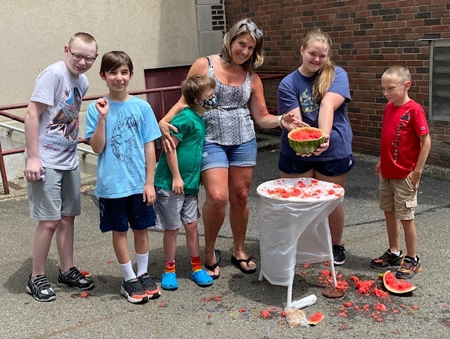 students and teacher pose with shattered watermelon