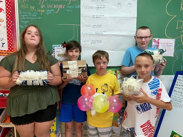 Students hold up egg drop creations
