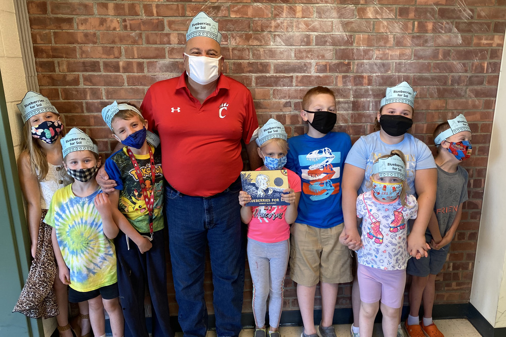 Man and students wearing masks and posing for photo
