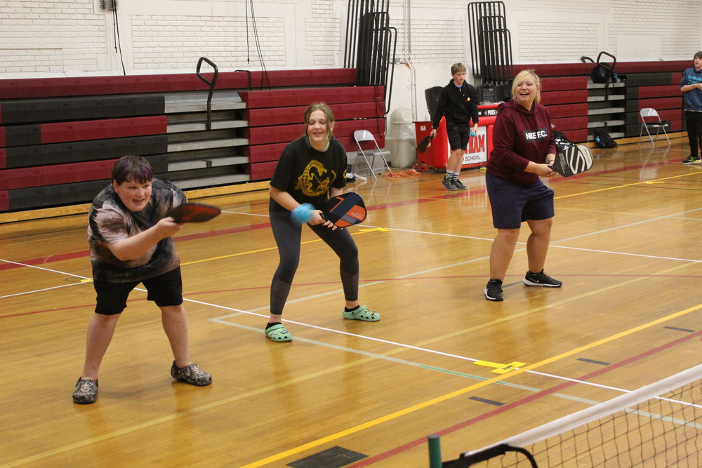 students and tea cher playing pickleball 