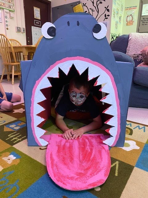Cardboard shark with boy inside