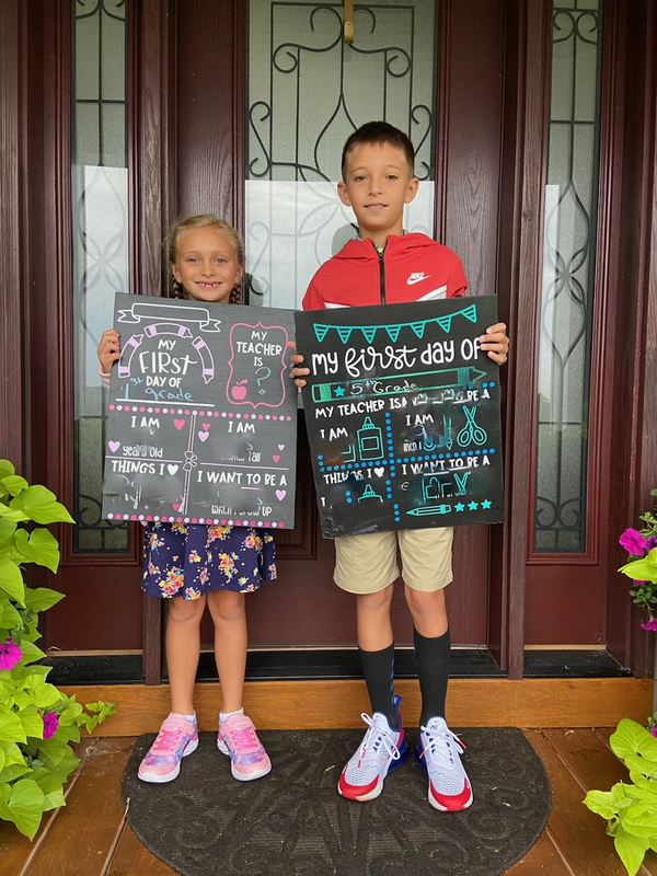 girl and boy holding first day signs