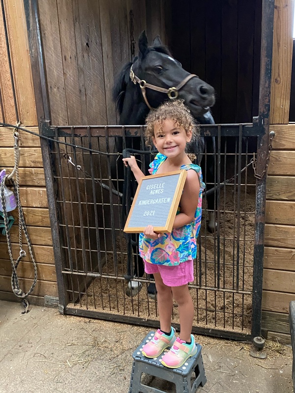 girl holding first day sign and standing in front of horse