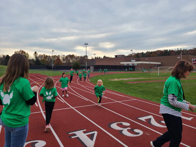 kids in green shirts running on track 