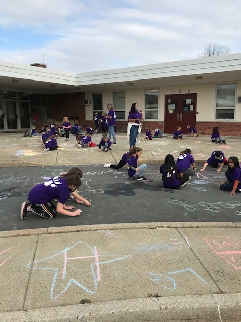 kids in purple shirts chalk drawing