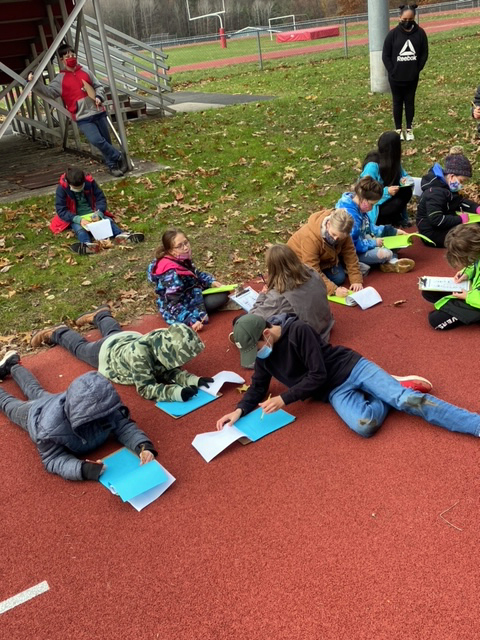 kids laying on athletic track writing in journals