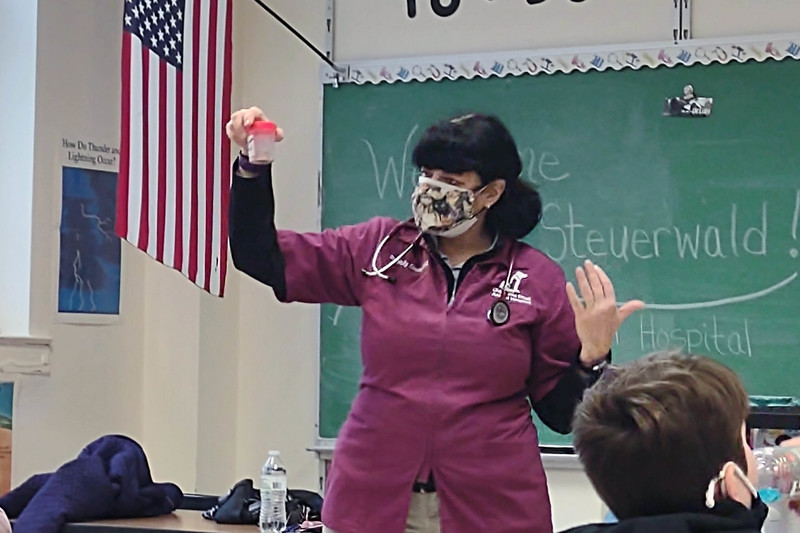 woman in scrubs holding up beaker  