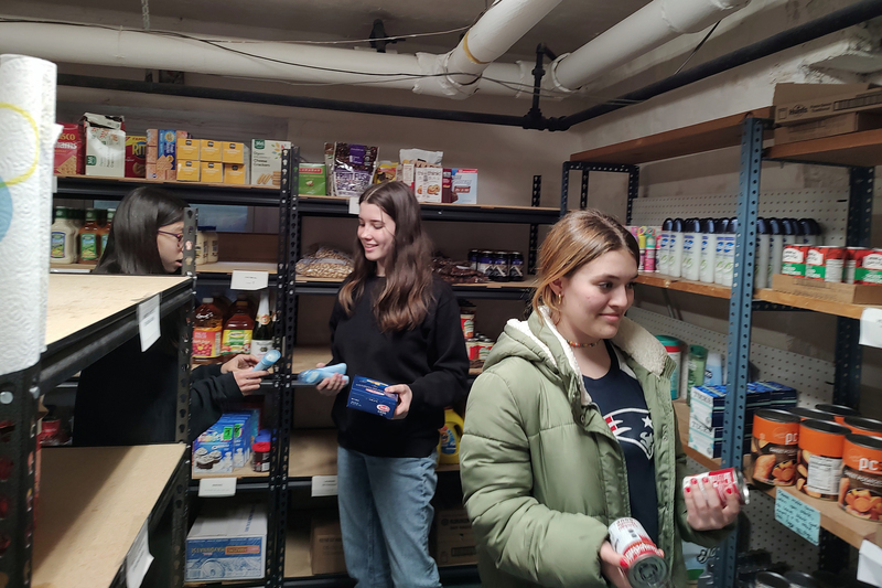 three girls stacking food pantry shelves