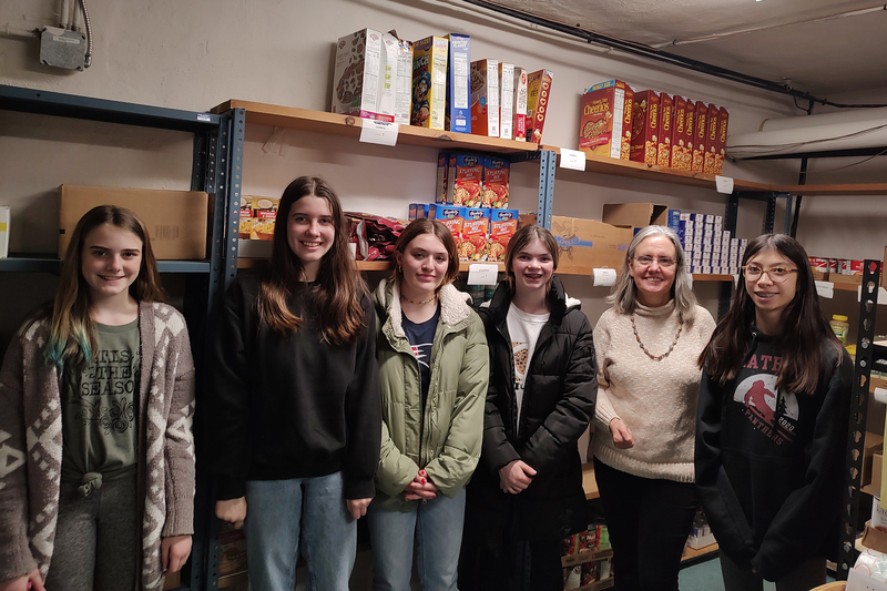 five girls and woman smiling in food pantry
