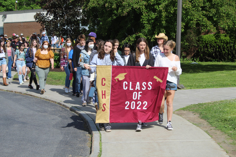 girls holding Class of 2022 banner lead procession out of school
