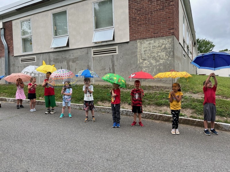 students holding umbrellas in parade around school