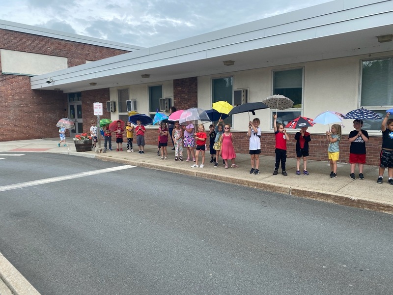 students holding umbrellas in parade around school