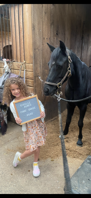 girl holding sign next to horse