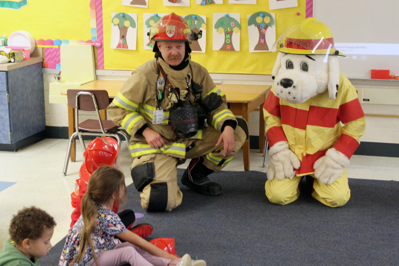 firefighter and dog mascot talk to students in classroom