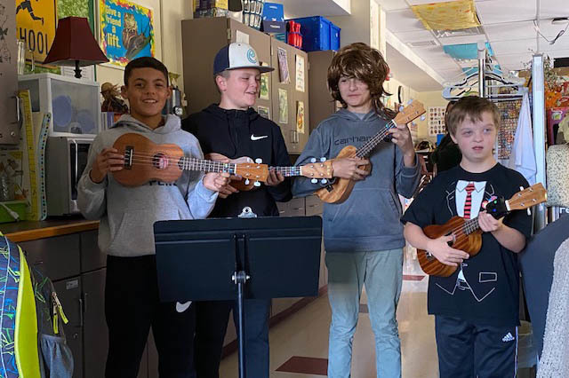 four boys holding ukuleles