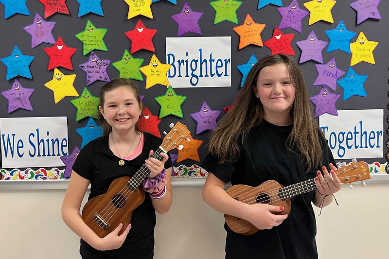 two girls holding ukuleles