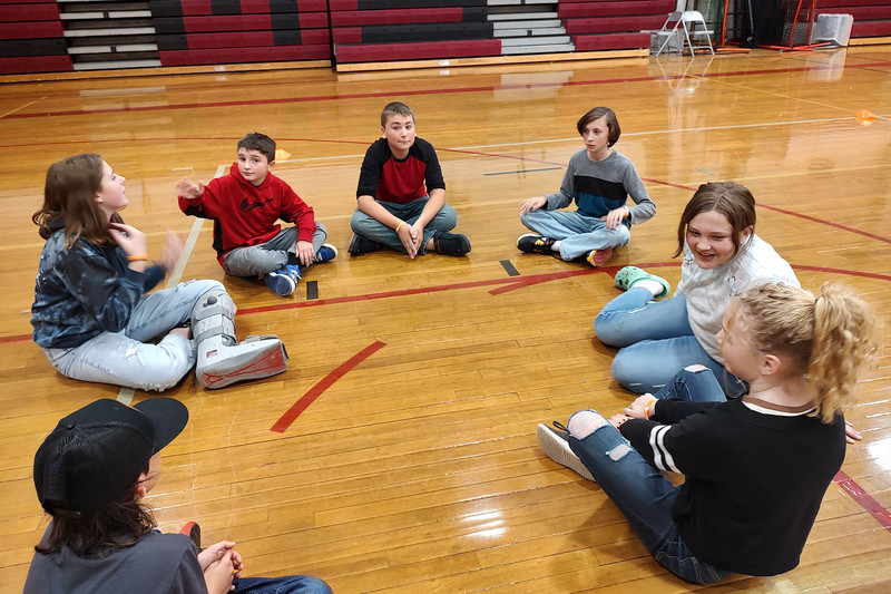 students sitting in circle on gym floor