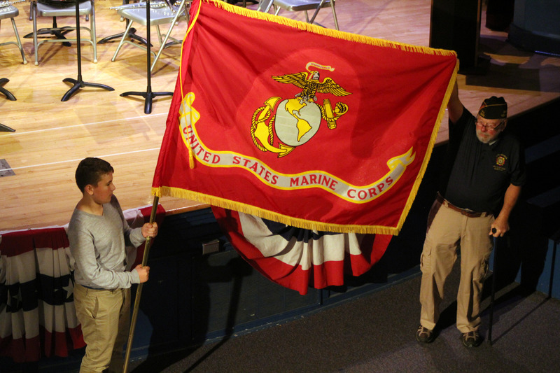 boy and veteran hold up USMC flag