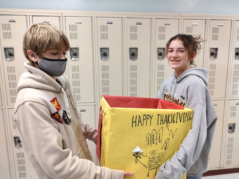 boy and girl carrying Thanksgiving box filled with food items