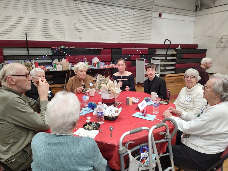 seniors eating dinner at table in gym