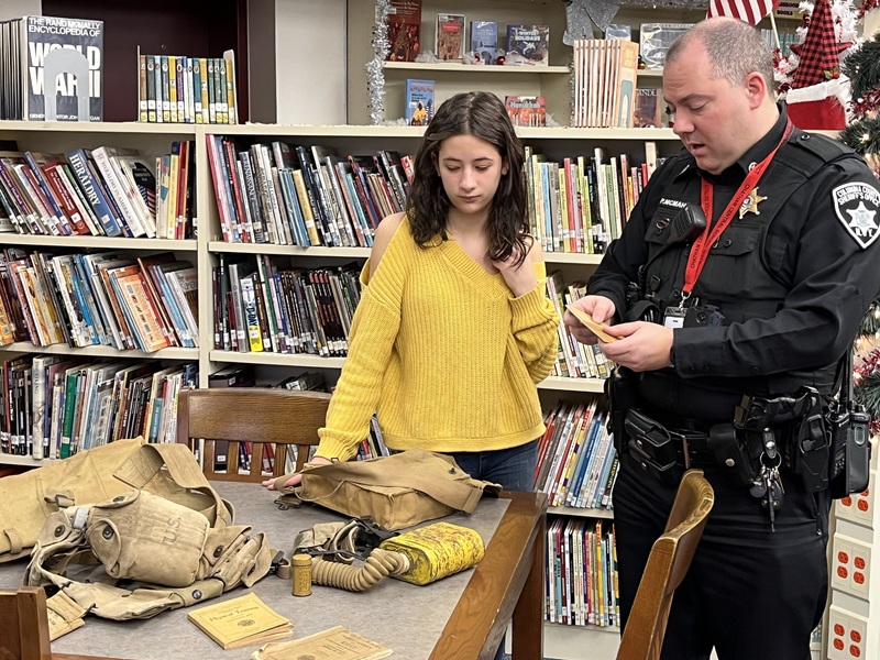 Deputy describing WWI items on table to student