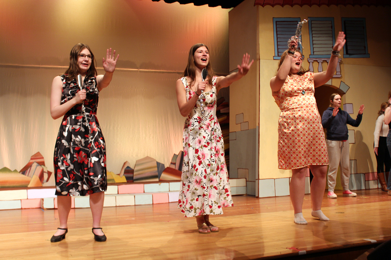 Three teenage girls singing on stage