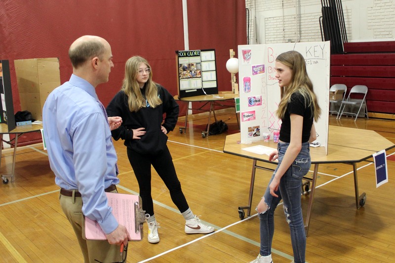 teacher discussing science fair project with two girls