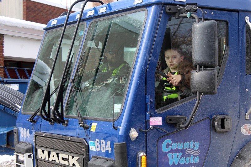 driver takes young boy for ride in garbage truck
