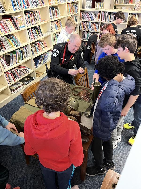 Police officer and students looking at militaria on table