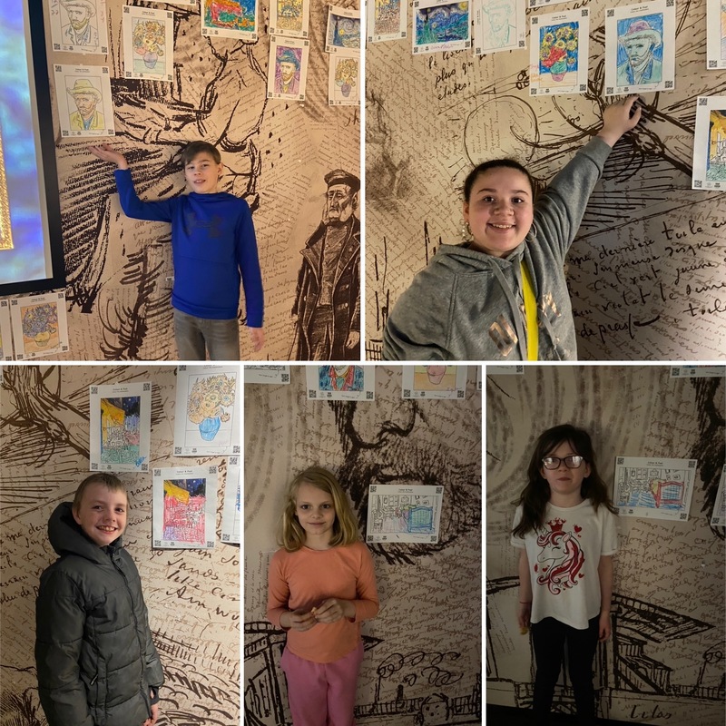 students pose with their drawing posted to exhibit wall