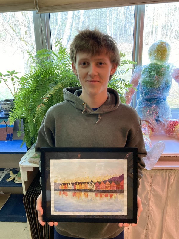 boy holding painting of row houses along waterfront
