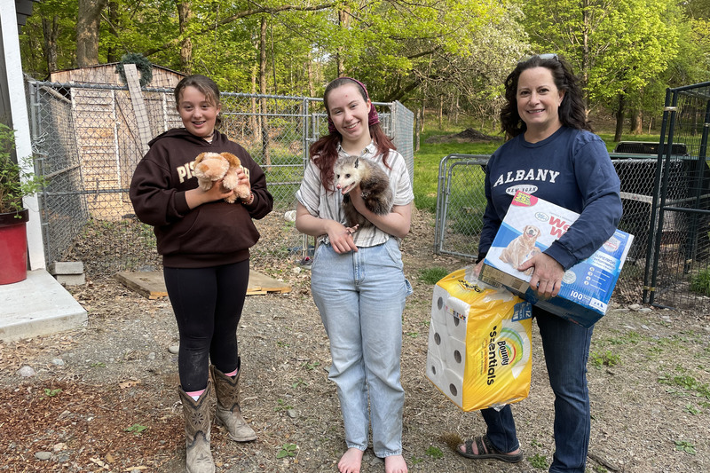 girls and two women holding donated supplies and opossum 