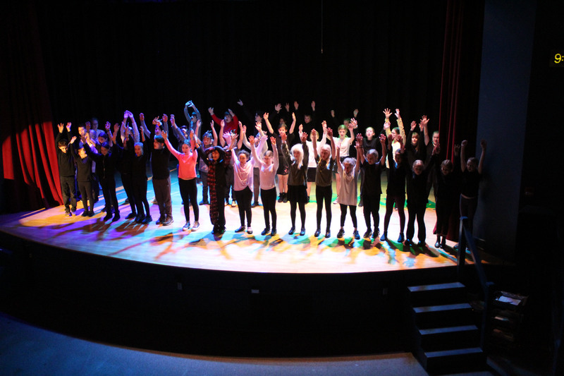 cast on stage doing show hands