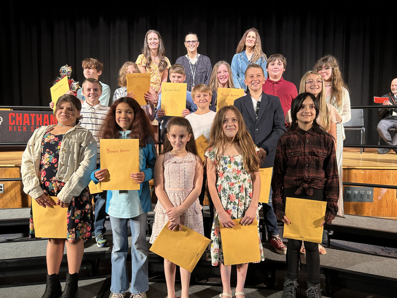 5th grade class poses with certificates on risers