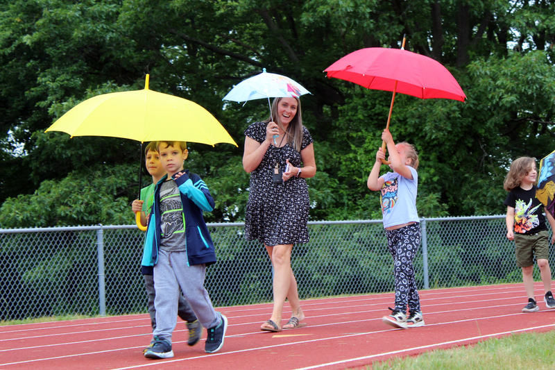 teacher and students walking with umbrellas
