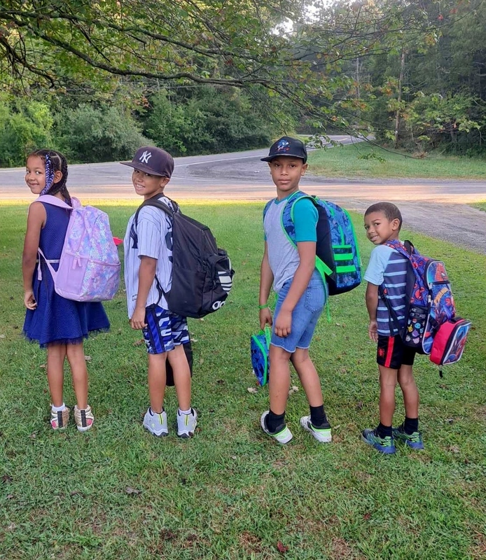 four students pose with backpacks