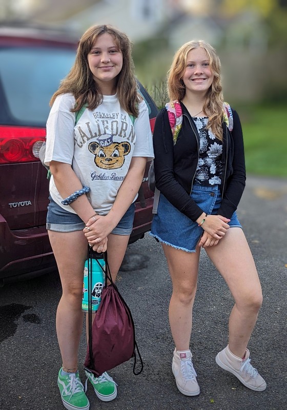 two girls smiling at bus stop