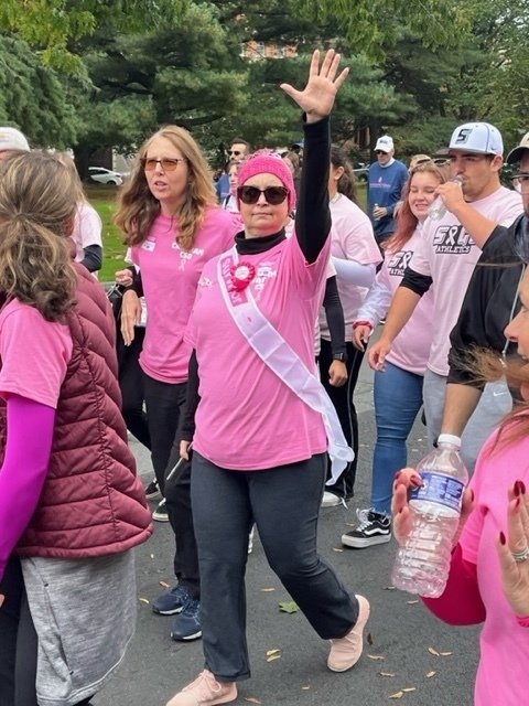 woman wearing pink shirt and waving camera