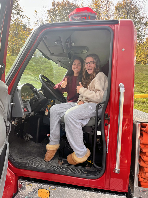 two teenage girls giving thumbs up from inside fire truck cab