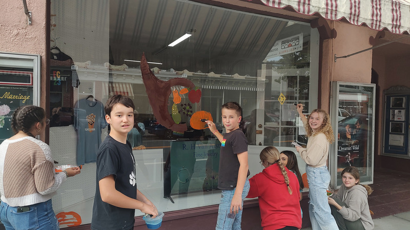 students painting cornucopia on shop window